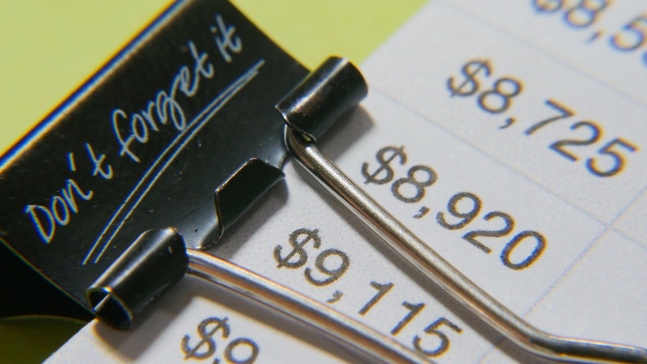 our-services-02 Close-up image showcasing a binder clip on a detailed financial report with highlighted amounts.